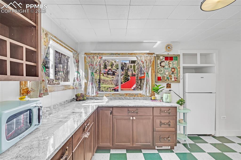 123 7th Street Victor, CO 80860 - Photo 30 of 50 Kitchen featuring white appliances, light floors, light stone countertops, and open shelves