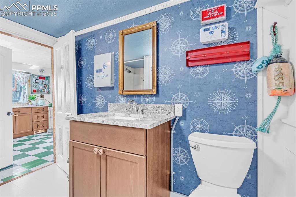 123 7th Street Victor, CO 80860 - Photo 39 of 50 Bathroom with tile patterned floors, toilet, vanity, wallpapered walls, and a textured ceiling