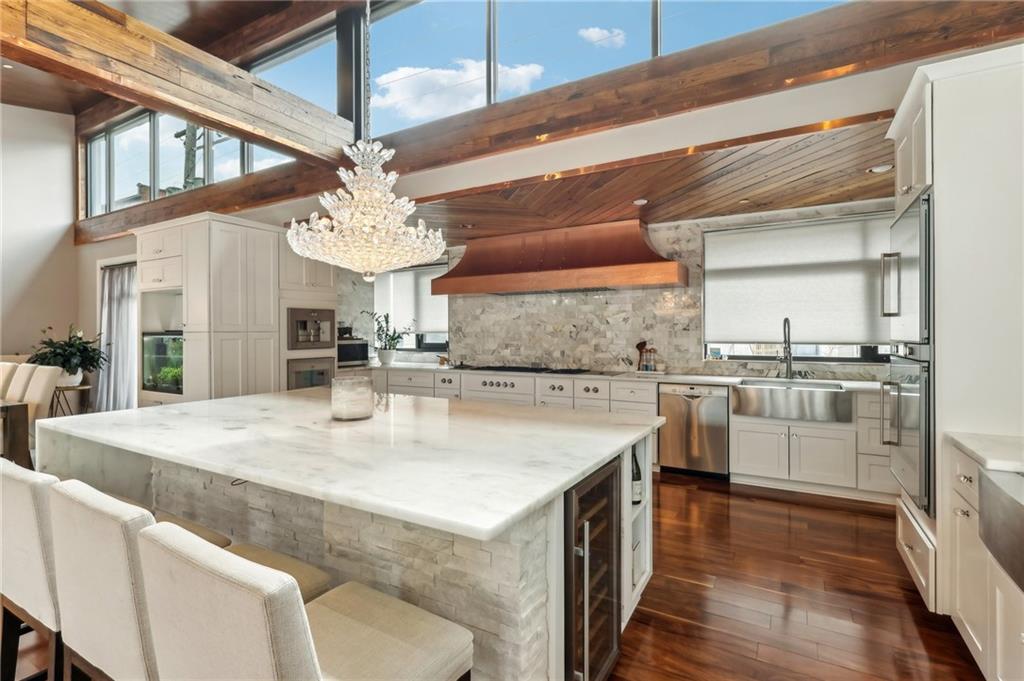 215 25th Street, Unit 7 Pittsburgh, PA 15222 - Photo 11 of 49 a kitchen with stainless steel appliances kitchen island granite countertop a sink dishwasher and white cabinets with wooden floor
