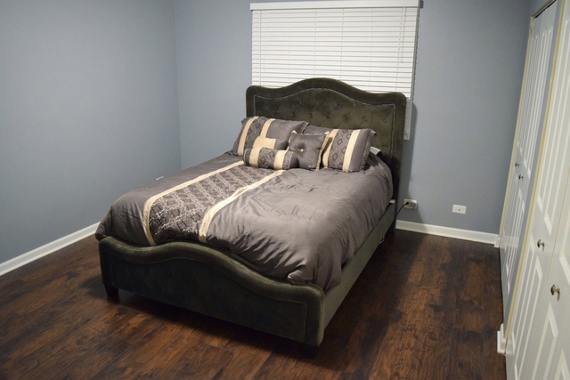 1905 West Golf Road, Unit 1A Mount Prospect, IL 60056 - Photo 20 of 24 a bed sitting in a bedroom next to a window with wooden floor