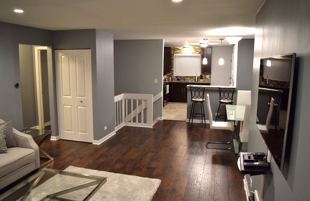 1905 West Golf Road, Unit 1A Mount Prospect, IL 60056 - Photo 4 of 24 a kitchen with stainless steel appliances granite countertop a refrigerator a stove top oven a dining table and chairs with wooden floor