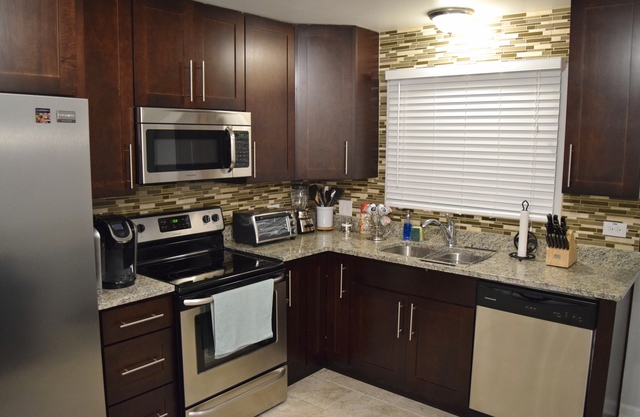1905 West Golf Road, Unit 1A Mount Prospect, IL 60056 - Photo 7 of 24 a kitchen with stainless steel appliances granite countertop a sink stove and microwave