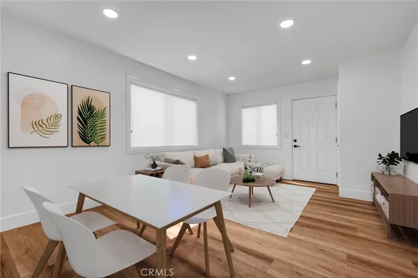 a living room with furniture a wooden floor and a potted plant