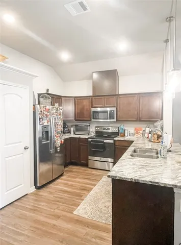 a kitchen with stainless steel appliances kitchen island granite countertop a refrigerator and a sink