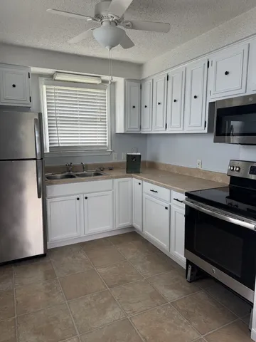 a kitchen with stainless steel appliances granite countertop a sink a stove a refrigerator and cabinets