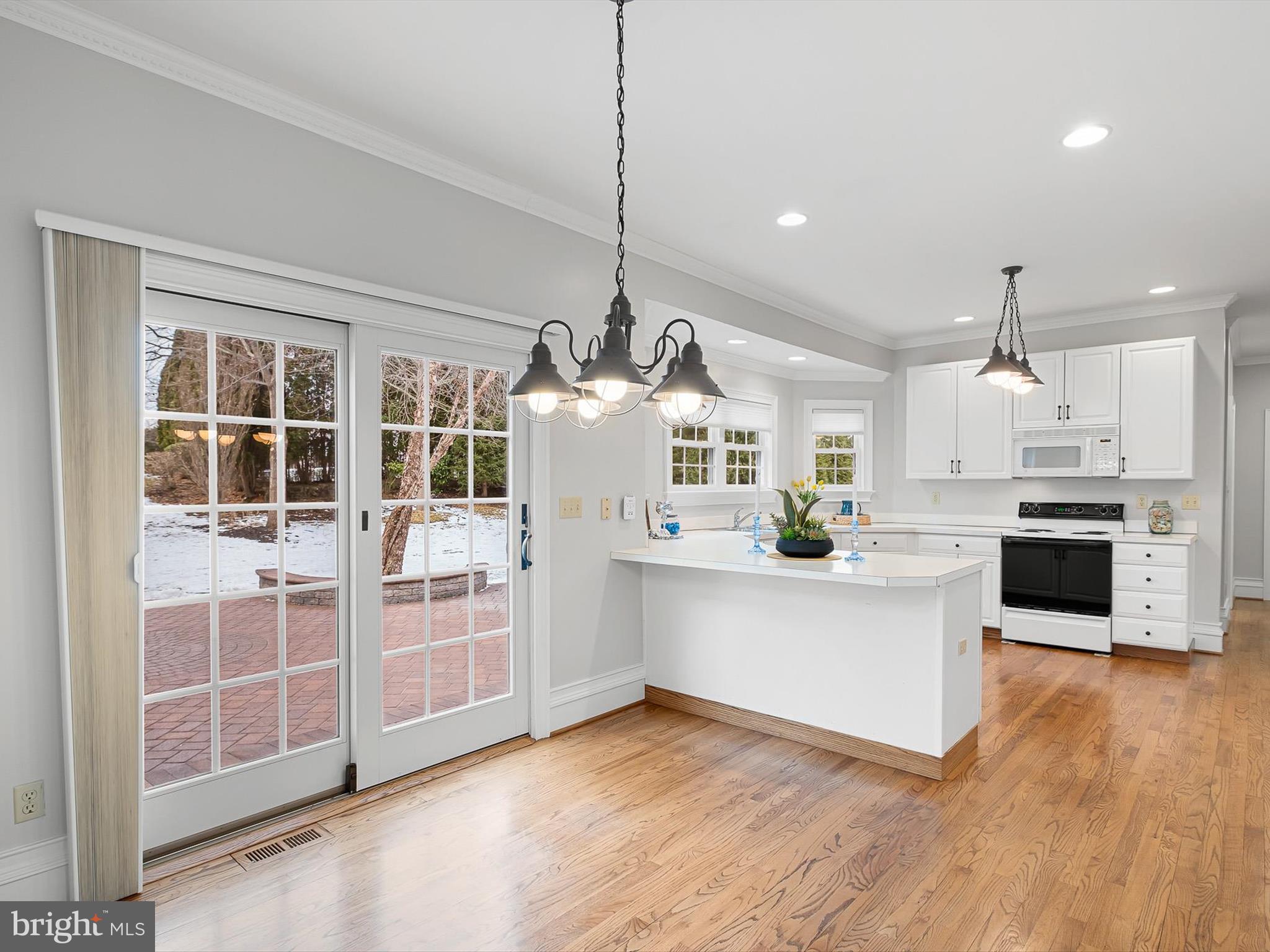 604 Oriole Place Hockessin, DE 19707 - Photo 9 of 40 a kitchen with kitchen island granite countertop a stove and white cabinets with wooden floor