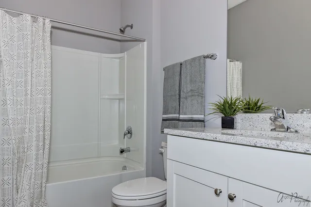 a bathroom with a granite countertop sink a toilet and shower