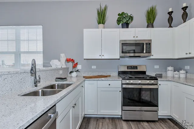a kitchen with granite countertop white cabinets stainless steel appliances and a sink