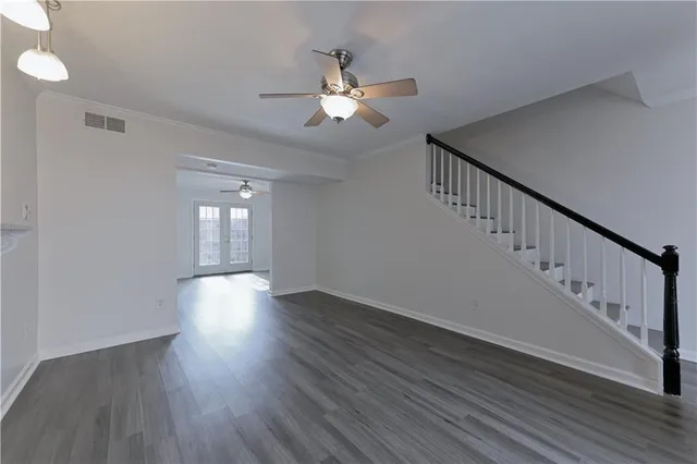 a view of an empty room with wooden floor and a chandelier fan