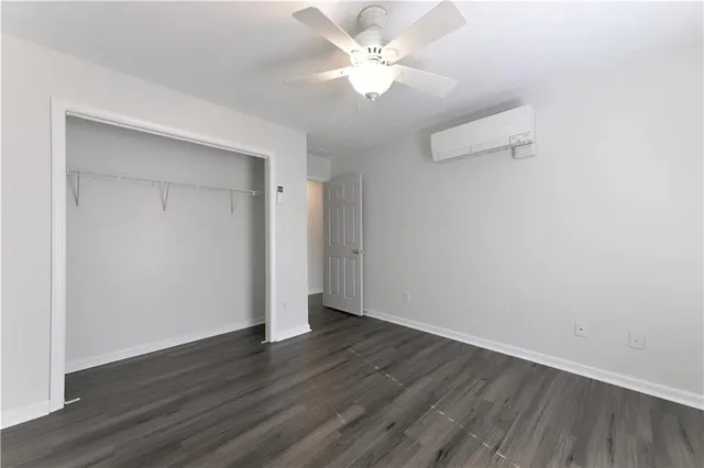 an empty room with wooden floor and fan