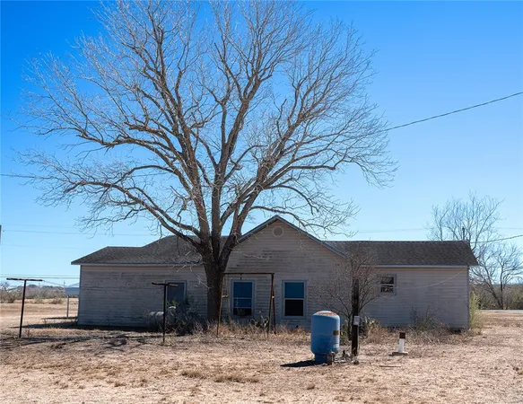 a view of a house with a yard and large tree