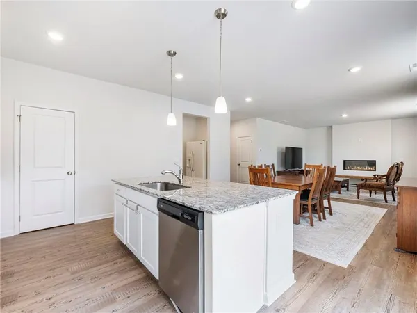 a kitchen with granite countertop a stove top oven a sink dishwasher and white cabinets with wooden floor
