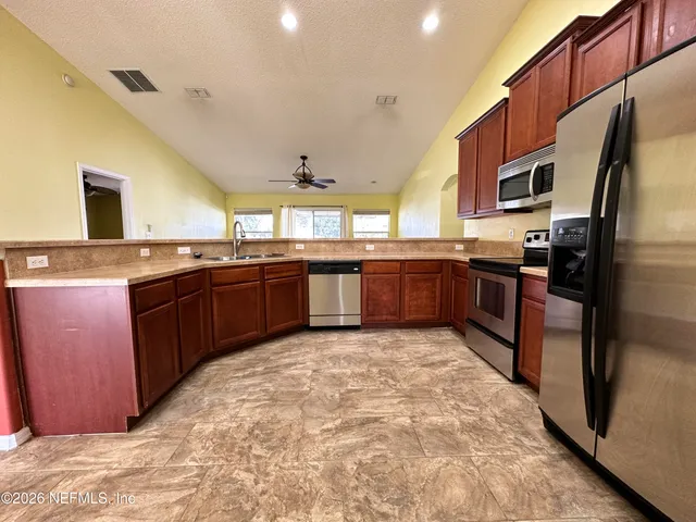 a large kitchen with wooden cabinets stainless steel appliances and a center island