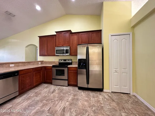 a kitchen with granite countertop a refrigerator and a stove top oven