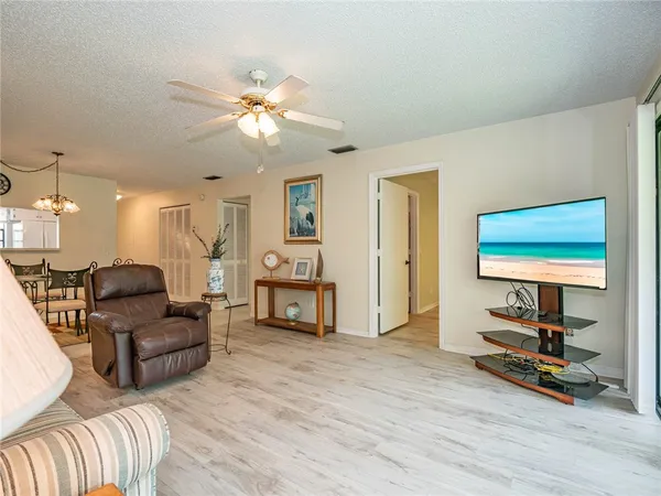 a living room with furniture a flat screen tv and a ceiling fan