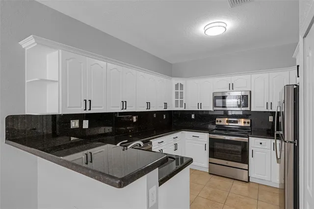 a kitchen with stainless steel appliances granite countertop a sink and white cabinets