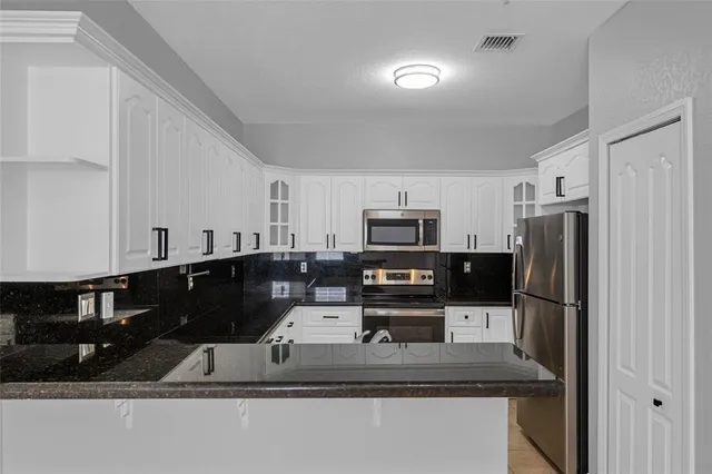 a kitchen with stainless steel appliances granite countertop a sink refrigerator and microwave