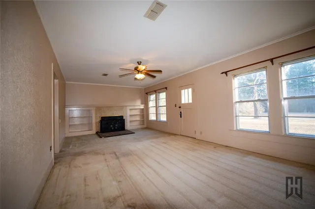 an empty room with windows and fireplace