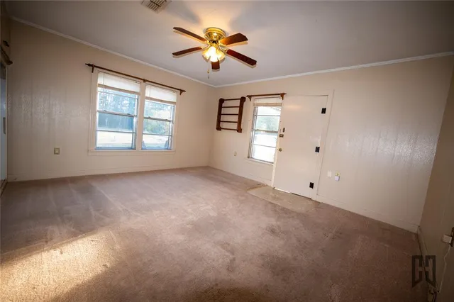 an empty room with windows and chandelier fan