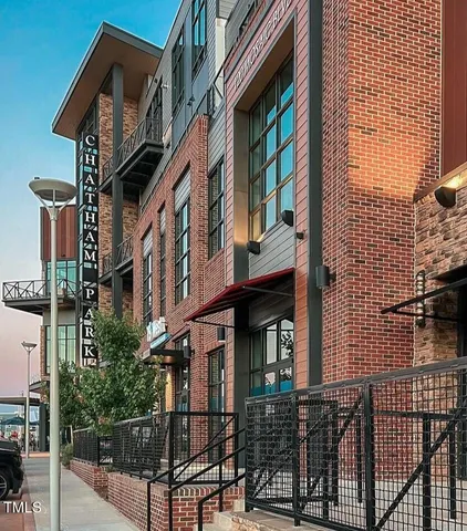 a very nice looking hall with kitchen island a large window a sink and a dining table with chandelier