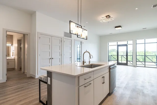 a kitchen with stainless steel appliances granite countertop a stove a sink dishwasher a dining table and chairs with wooden floor