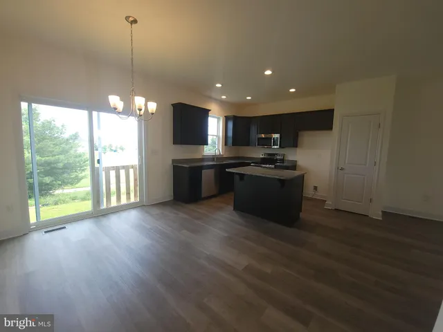 a open kitchen with kitchen island a stove a sink a refrigerator wooden floor and a large window