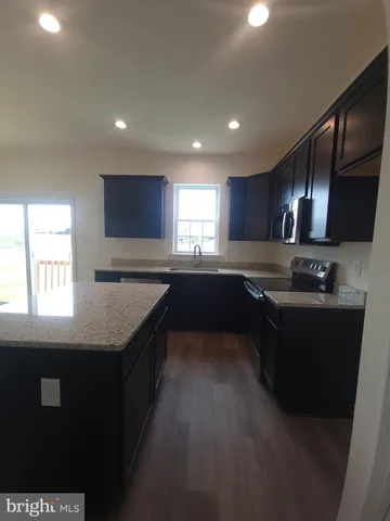 a kitchen with stainless steel appliances granite countertop a sink a stove top oven and a refrigerator