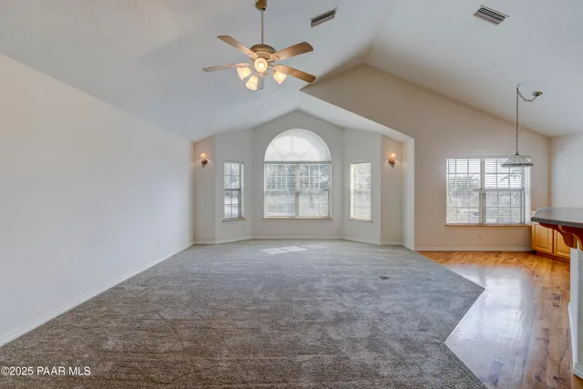 an empty room with a chandelier fan and windows