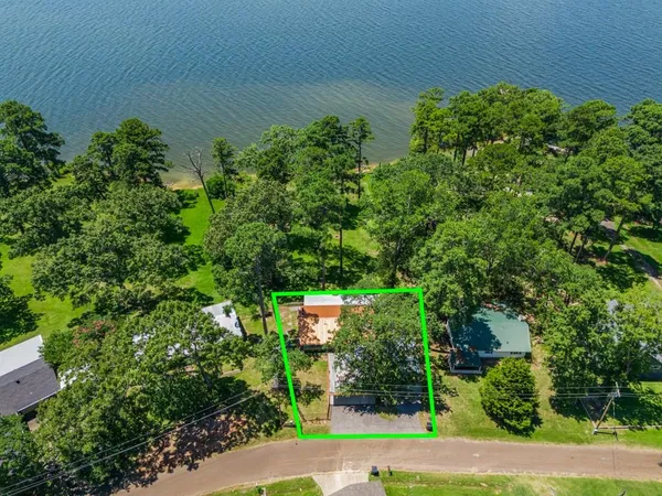 an aerial view of a house with a yard and trees all around