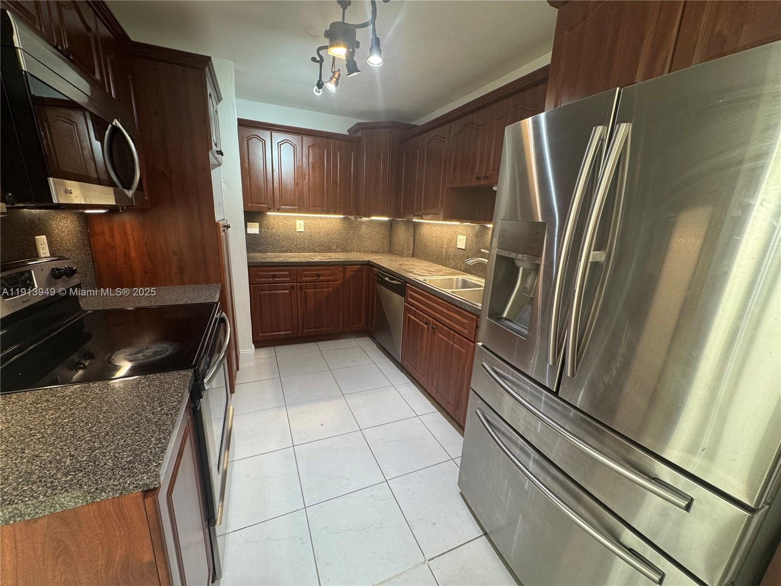29523 Southwest 144th Court Homestead, FL 33033 - Photo 6 of 59 a kitchen with granite countertop stainless steel appliances a sink stove and refrigerator