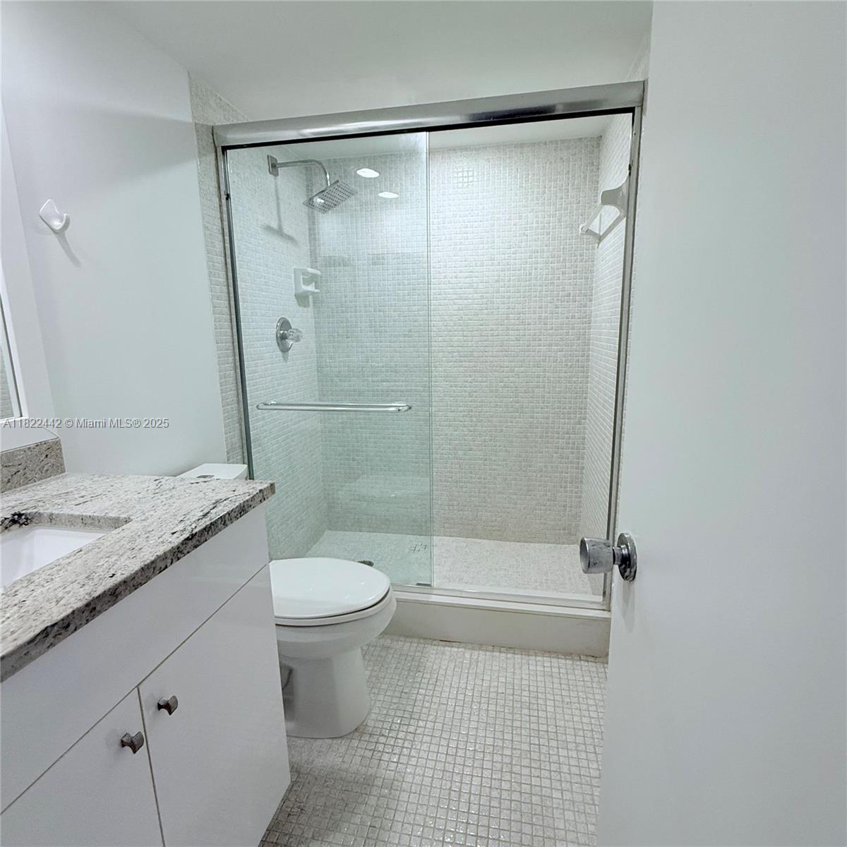 3980 Oaks Clubhouse Drive, Unit 302 Pompano Beach, FL 33069 - Photo 6 of 15 a bathroom with a granite countertop sink toilet and shower