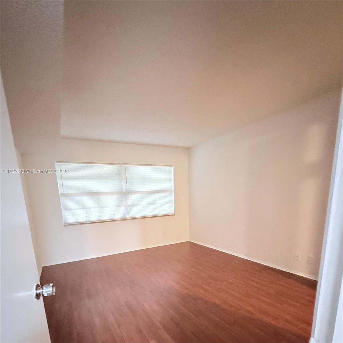 3980 Oaks Clubhouse Drive, Unit 302 Pompano Beach, FL 33069 - Photo 8 of 15 an empty room with wooden floor and windows