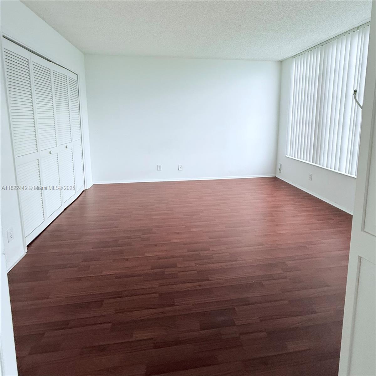 3980 Oaks Clubhouse Drive, Unit 302 Pompano Beach, FL 33069 - Photo 9 of 15 a view of an empty room with wooden floor and a window