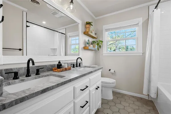 a bathroom with a granite countertop sink a large mirror a toilet and a window