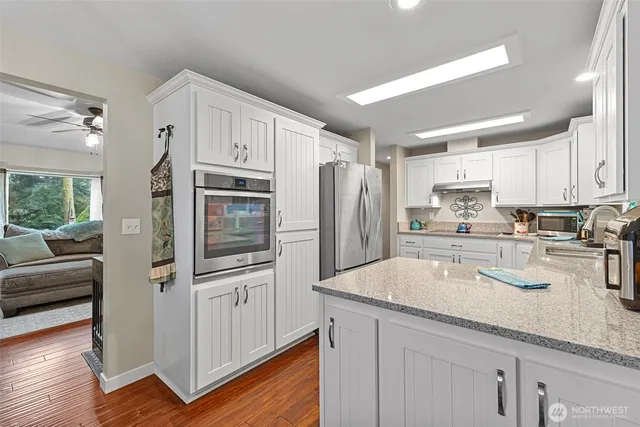 a kitchen with granite countertop a refrigerator a sink a stove and white cabinets