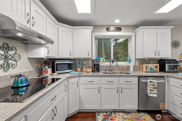 a kitchen with stainless steel appliances granite countertop a stove a sink and white cabinets