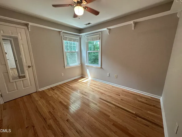 a view of an empty room with a window and wooden floor