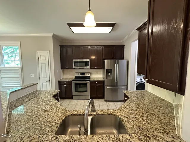 a kitchen with stainless steel appliances granite countertop a refrigerator a stove and a sink with wooden floor