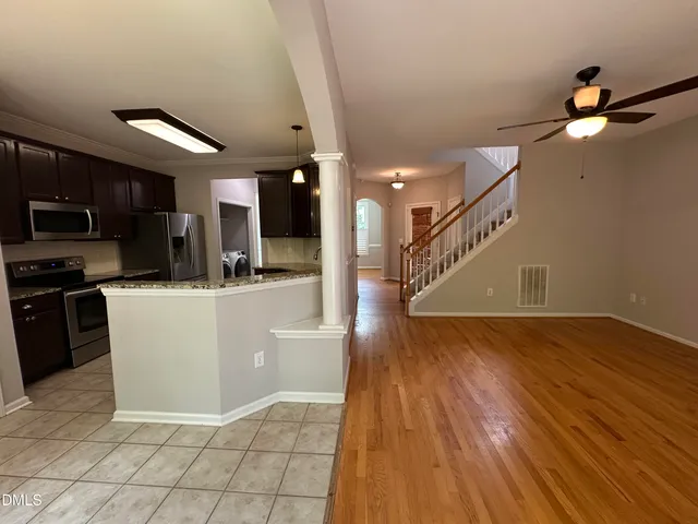 a view of empty room with wooden floor and fan