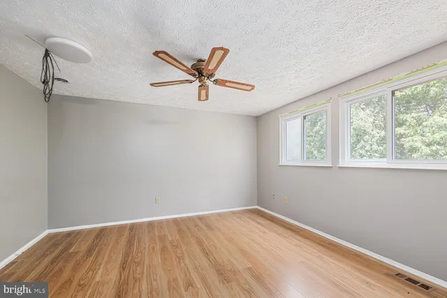 an empty room with a window and a ceiling fan
