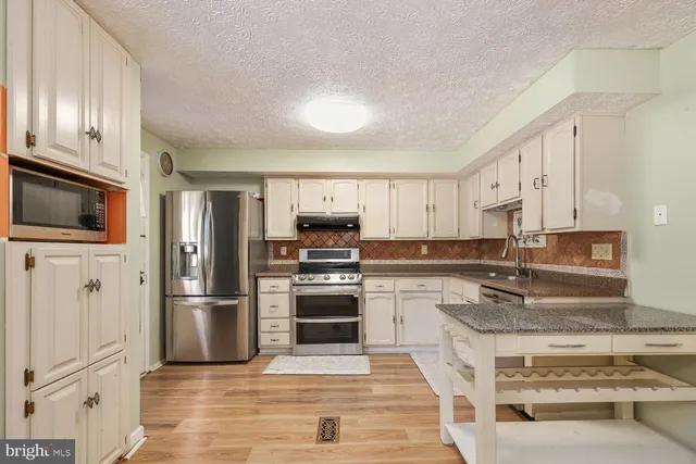 a kitchen with granite countertop a refrigerator stove and microwave