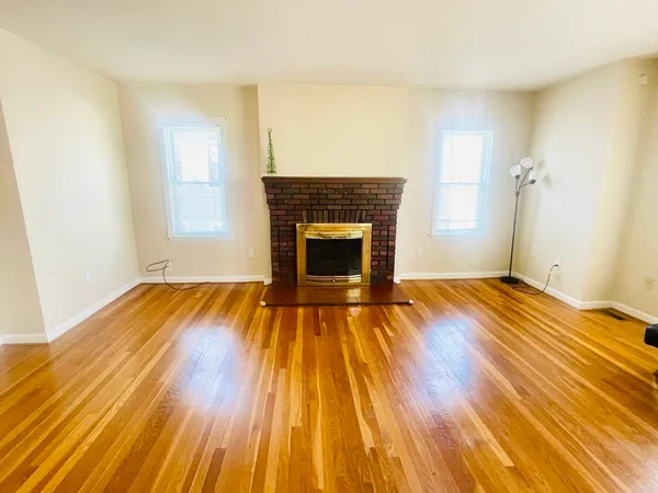 an empty room with wooden floor and fireplace