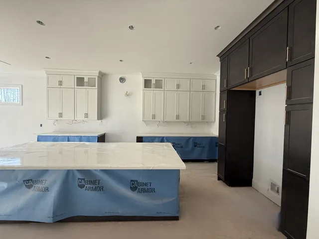 a living room with stainless steel appliances kitchen island granite countertop a refrigerator a stove a sink and white cabinets