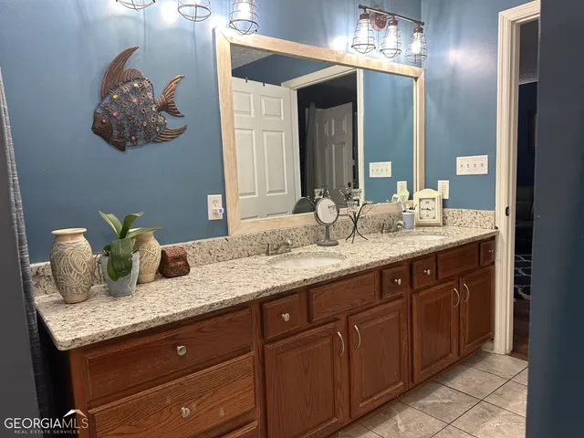 a bathroom with a granite countertop double vanity and a mirror