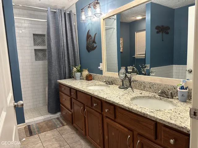 a bathroom with a granite countertop double vanity sink and a mirror
