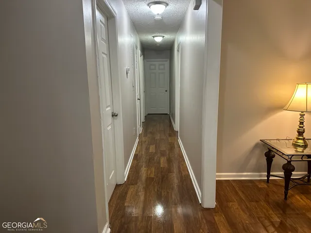 a view of a hallway with wooden floor and a bathroom