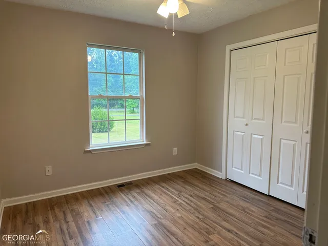 an empty room with wooden floor and windows