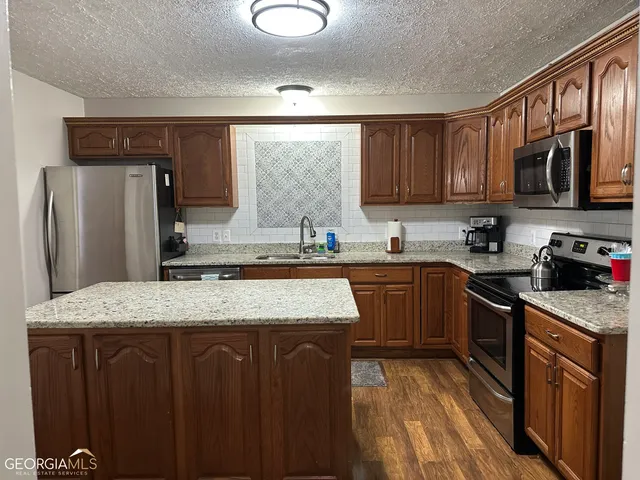 a kitchen with stainless steel appliances granite countertop wooden cabinets a refrigerator and a sink