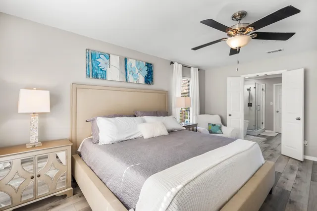 a bedroom with a large bed and a chandelier fan