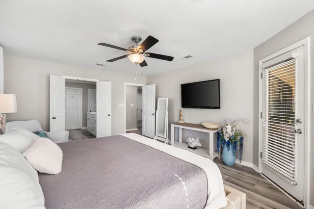 a bedroom with a bed television on desk and a window